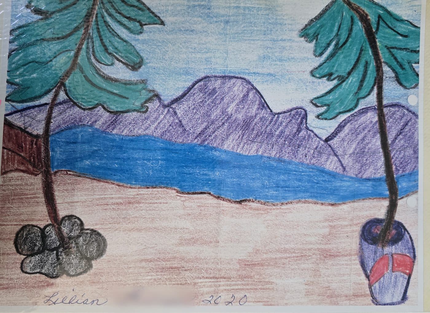 A patient's crayon drawing of a beach, with palm trees framing a blue lagoon and purple mountains, sent to the practice in 2020.