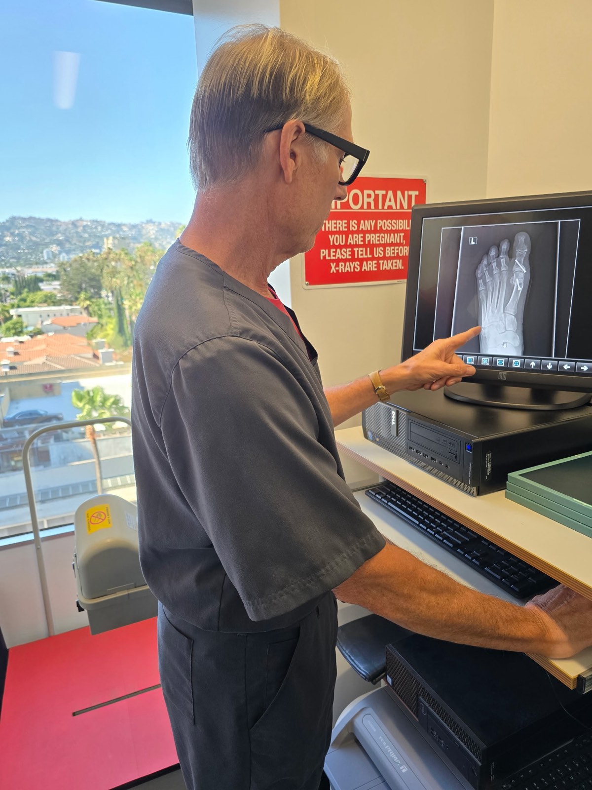 Dr. Timothy Liddy pointing to a foot X-ray on a monitor in the Beverly Hills office