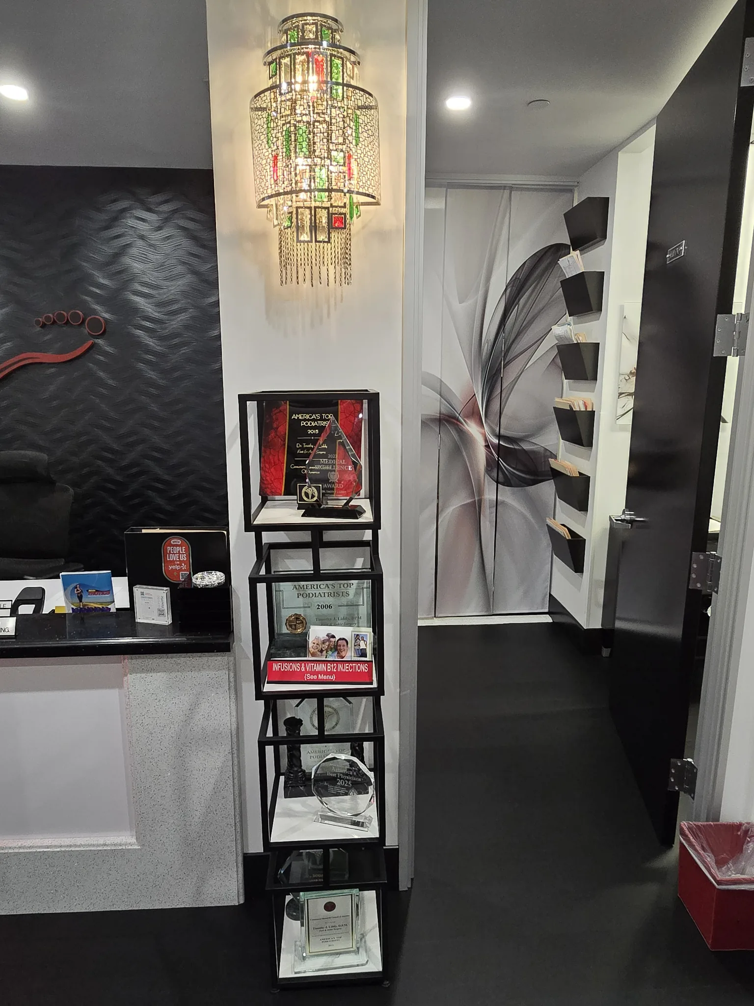 Corridor inside Liddy Podiatry with a display shelf of awards and a decorative chandelier