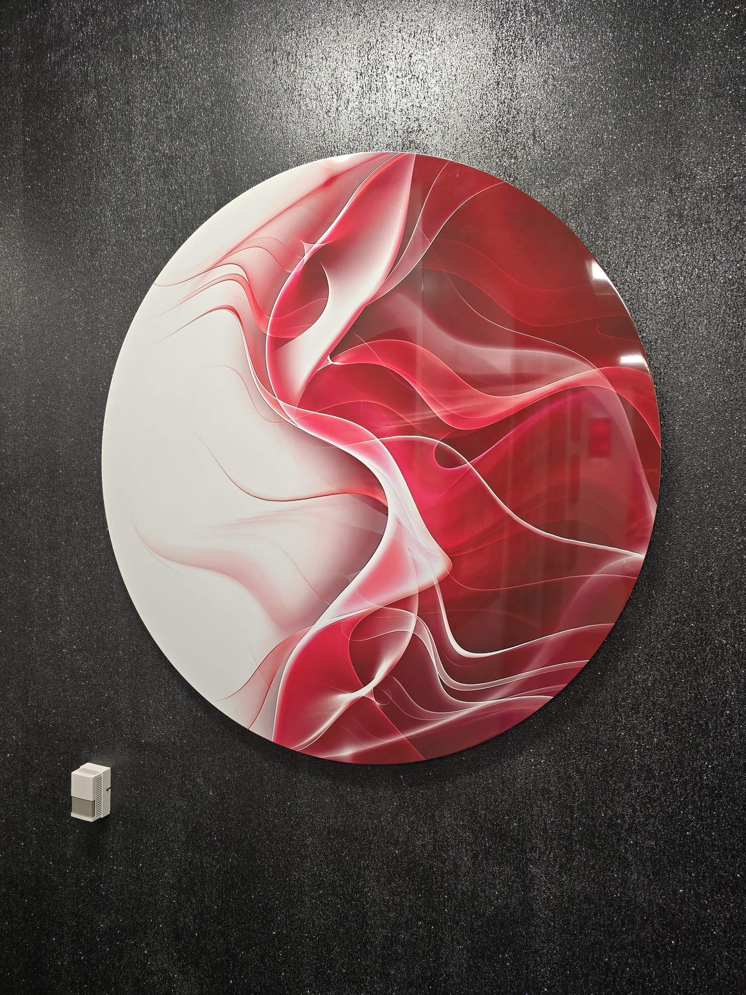 Large circular red and white abstract artwork on a dark textured wall