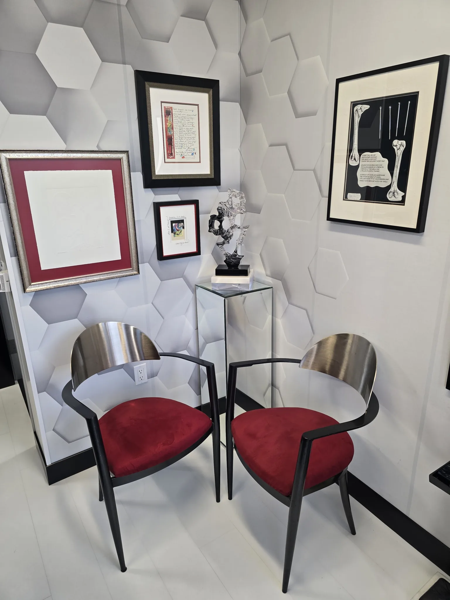 Seating corner with two red and steel chairs beneath framed artwork